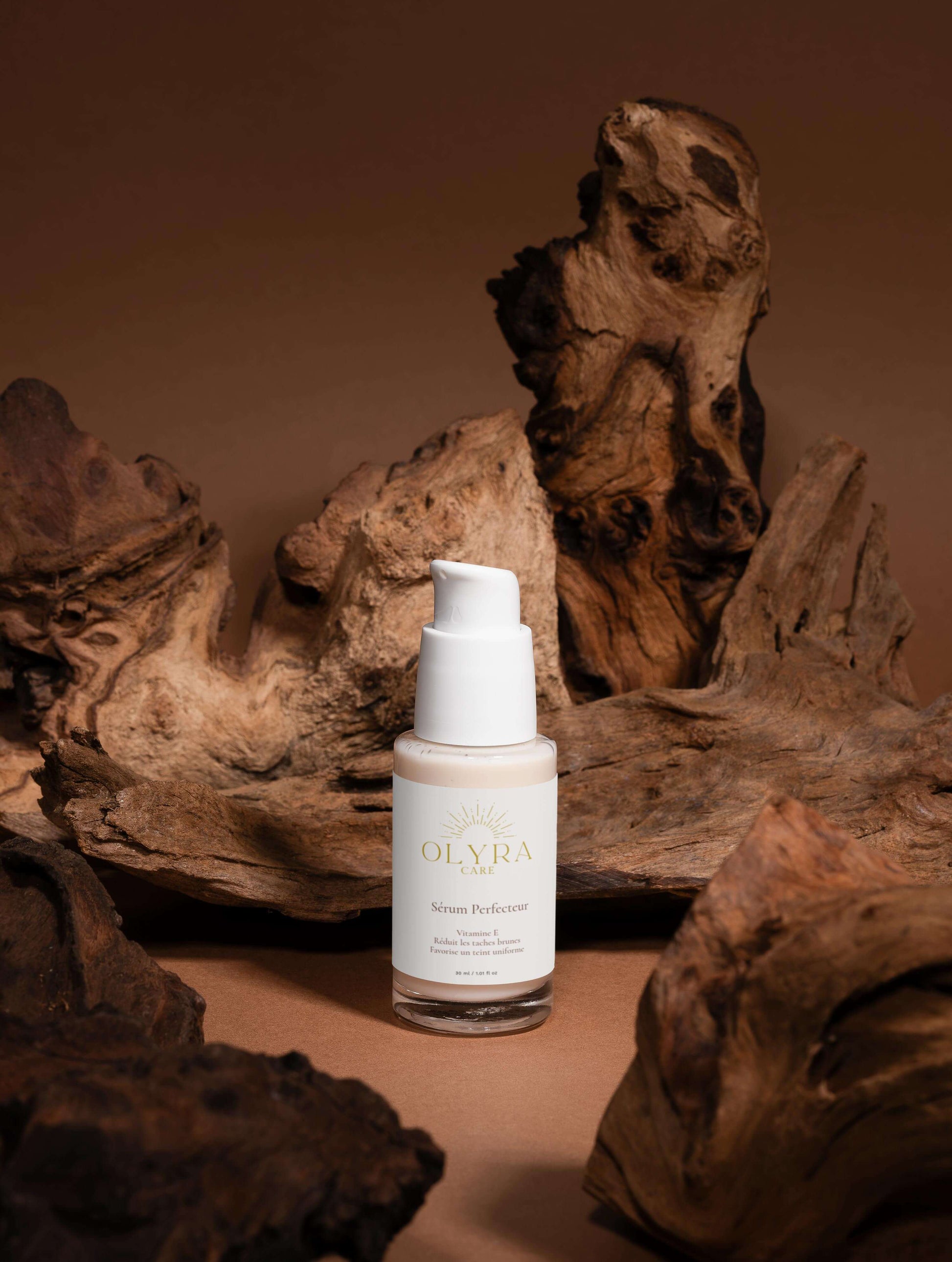 Sérum Perfecteur Visage OLyra Care sur un fond en bois, conçu pour unifier le teint et réduire les taches brunes.