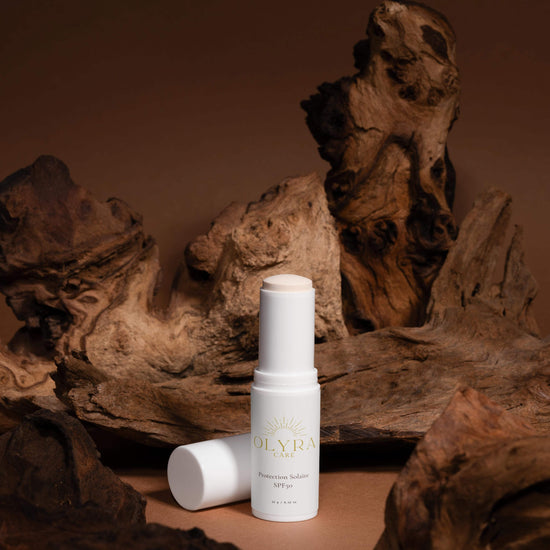 Protection solaire visage SPF50 en stick Olyra Care sur fond naturel en bois.